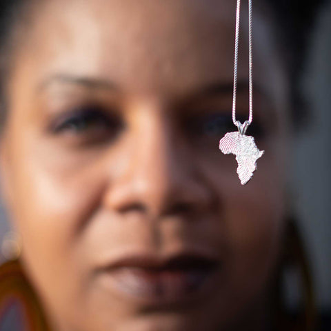 African American woman showing a silver Africa map pendant with chain