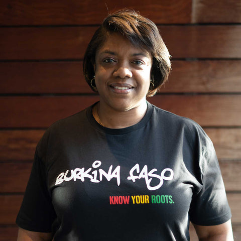 African American woman wearing a Burkina Faso T-shirt  with "Know Your Roots" written in African colors