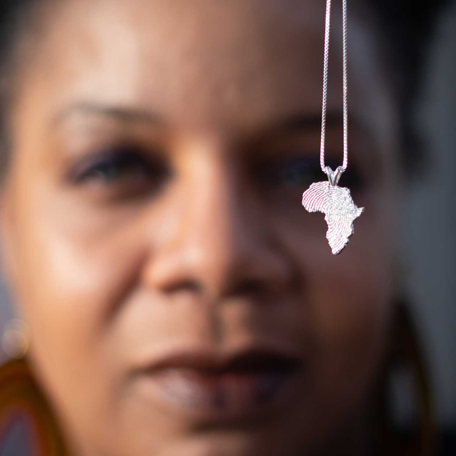 African American woman showing a silver Africa map pendant with chain