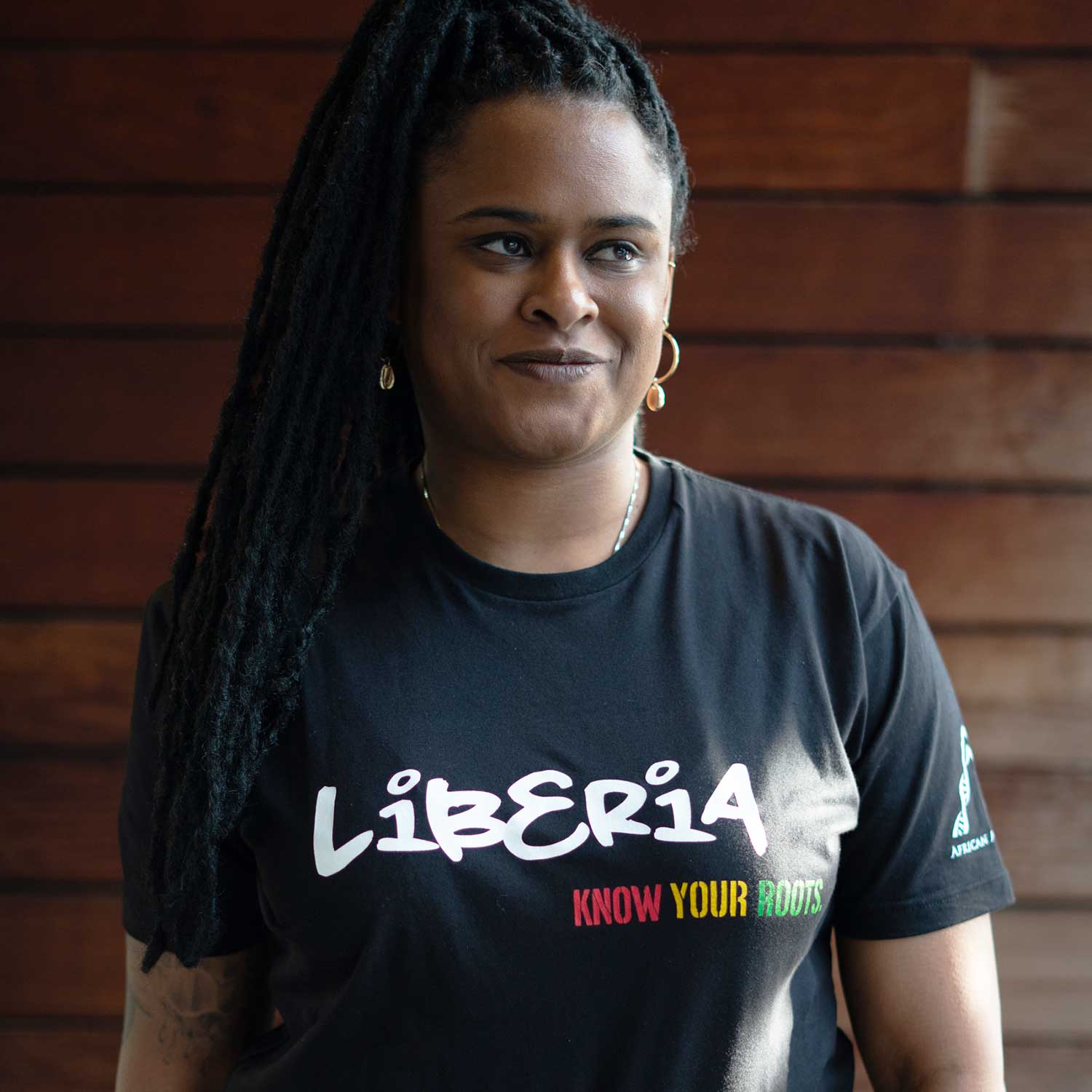 African American woman wearing a black T-shirt with "Liberia" written in white and "Know your roots" written in African colors